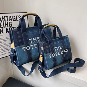 Detailed close-up of blue denim tote bags in two sizes featuring bold white printed text