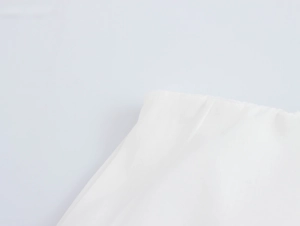 Close-up of white cotton fabric texture and hem detail on a vacation style set