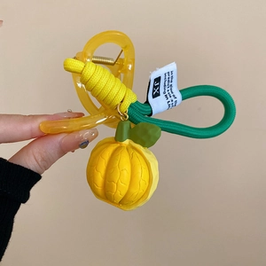 Detail of yellow acrylic hair claw clip with fruit charm and woven rope accents