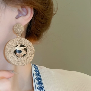 Détail macro de boucles d'oreilles bohèmes en raphia avec accents imprimé léopard