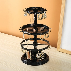 Rotating tiered jewelry organizer for earrings and necklaces on a wooden surface