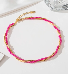 Detail of pink beads and gold square metal blocks on a layered necklace design