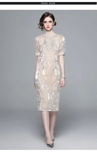 Detail of embroidered sequin top and high-waist split skirt with tassel accents