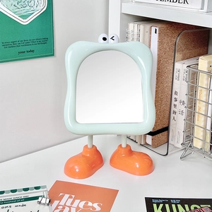 Cartoon desktop makeup mirror with green wavy frame and orange foot-shaped stand