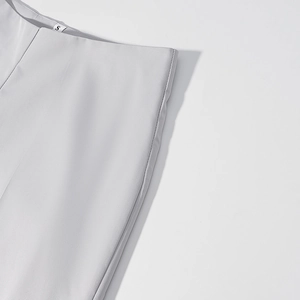 Detail of light grey straight-leg pants waistline with size S tag and fine stitching