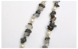 Gros plan de perles en quartz rutilé noir et perles blanches sur une dragonne mobile