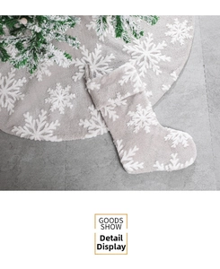 Detail of plush grey Christmas stocking and tree skirt set with white snowflake patterns