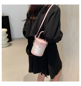 Pink bucket bag with jacquard fabric detail worn over the shoulder on a black coat