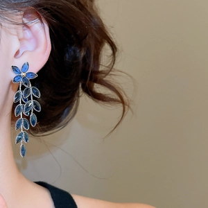 Nahaufnahme eleganter Blumenohrringe mit blauen Kristallquasten an einem Model