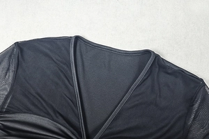 Detail of V-neck stitching and sheer mesh sleeve texture on a black slim-fit dress