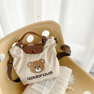 Detalle de la bolsa de pañales de lona beige con patrón de oso pardo y estampado UDUDFOUB