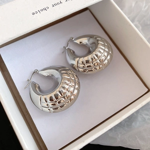 Detail of silver hoop earrings with textured geometric pattern displayed in a gift box