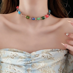 Close-up of colorful patterned glass beads on a metal chain worn by a fashion model