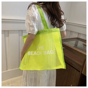 Detail of neon green mesh beach bag featuring large white The Beach Bag lettering