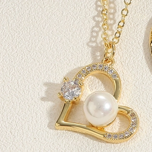 Macro shot of gold heart pendant with white pearl and sparkling zircon details