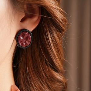 Close-up of geometric irregular earrings with wine red texture and black frame
