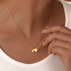 Detail of 18K gold plated heart and bar pendants necklace on model for women
