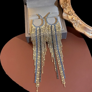 Detail of gold tassel earrings with emerald stones on a heart-shaped cushion