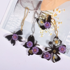 Detailed view of resin butterfly pendants with dried flowers and ball chains for keychains