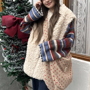 Close-up of beige plush vest and matching crossbody bag with a festive holiday backdrop