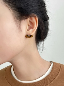 Detailed close-up of tiger eye stone curved earrings on a model showing vintage texture