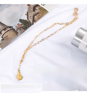 Gros plan d'un collier en acier titane doré avec un pendentif en forme de cœur à la main