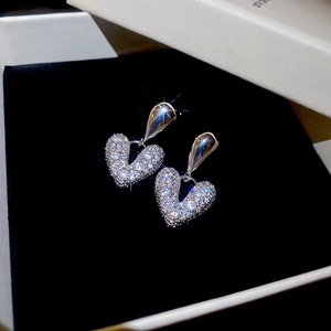 Boucles d'oreilles cœur argentées scintillantes avec zircons dans un coffret à bijoux