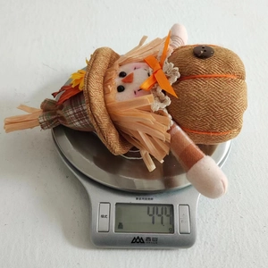 Detailed view of fall scarecrow doll weighing 44.4g on a digital kitchen scale