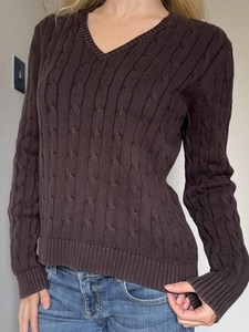 Détail d'un pull marron en maille torsadée avec col en V et finitions côtelées
