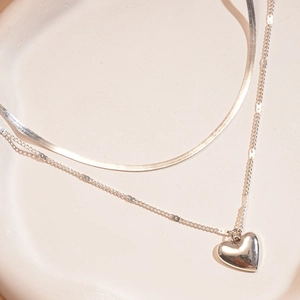 Detail shot of double-layered silver necklace with snake chain and polished heart pendant