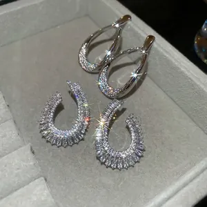 Sparkling silver zircon teardrop and U-shaped earrings displayed in a grey jewelry tray