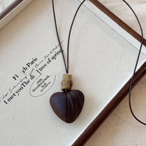 Detail of dark wood heart pendant with bamboo-style joint on a fine brown necklace cord