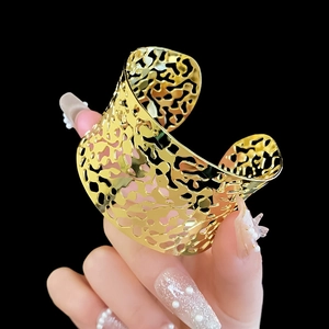 Detailed view of a gold wide cuff bracelet with an irregular mesh cutout design