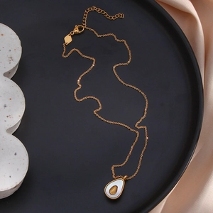 Detail of avocado pendant necklace in gold stainless steel on elegant silk background