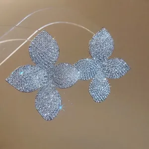 Orecchini a lobo a forma di fiore d'argento con cristalli scintillanti su fondo beige