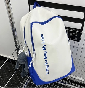 Detail of blue and white canvas backpack with plush frog charm in a metal cart
