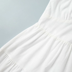 Close-up of white cotton dress showing tiered ruffle details and textured woven fabric