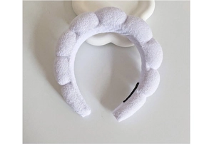 Close-up of a plush white sponge cloud headband with soft towel fabric on a white tray