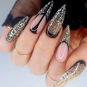 Macro shot of long stiletto press-on nails with black French tips and gold glitter detail