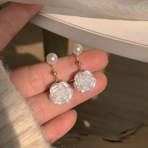 Detail of camellia flower earrings with a pearl top and white petals in natural light