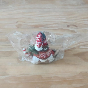 Detail of Christmas gnome figurine with red and white knit hat and candy cane decor