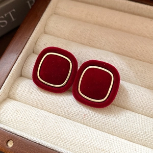 Close-up of vintage square burgundy velvet stud earrings with golden metallic frames
