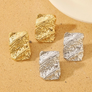 Detailed view of square textured earrings in gold and silver with hammered finish