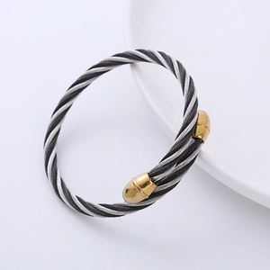 Detailed close-up of twisted silver and black cable cuff with gold conical end caps