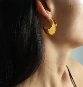 Detailed close-up of a polished gold crescent moon earring with a minimalist mirror finish