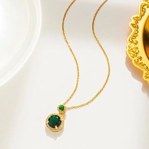 Detailaufnahme einer Goldkette mit smaragdgrünem Edelstein und kleinen Diamanten verziert