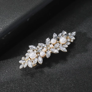 Vue macro d'une barrette en forme de feuille avec strass brillants et perles blanches
