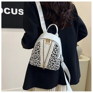 Detail view of stylish leopard print and white leather backpack with golden zippers