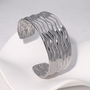 Gros plan détaillé du bracelet ouvert en acier inoxydable argenté à texture fluide
