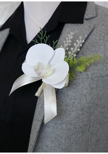 Detail of white orchid boutonniere with green leaves on grey suit lapel for weddings